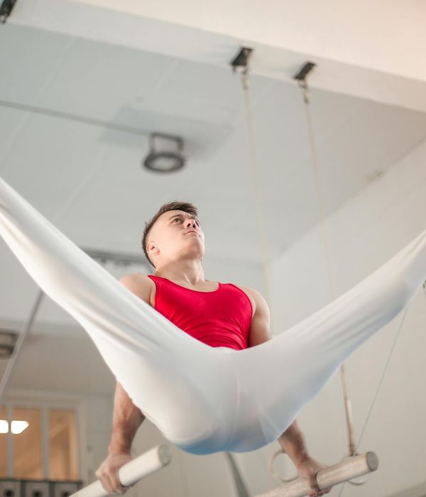 Man performing a controlled strength exercise in a dark gym.
